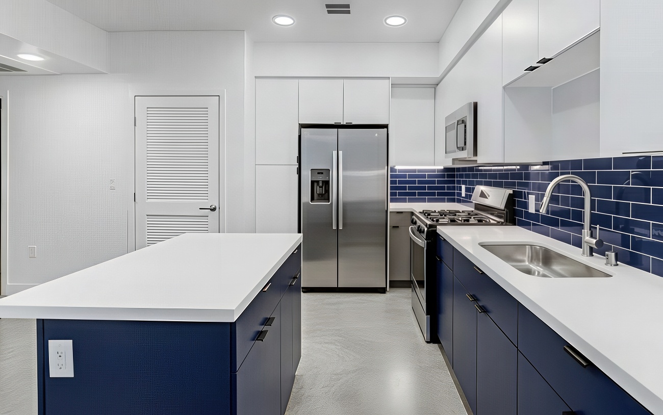 Modern apartment kitchen with navy cabinets, blue subway tile, and stainless appliances.